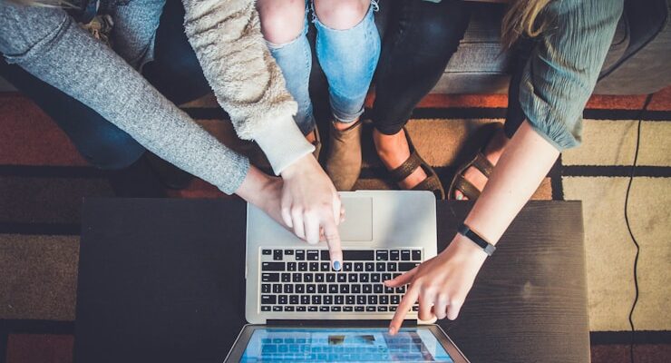 three person pointing the silver laptop computer